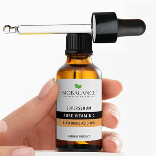 Sticla BioBalance SuperSerum Pure Vitamin C cu pipeta, tinuta in mana, pe fundal alb