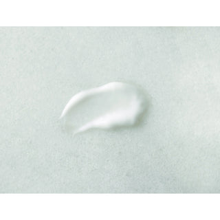 A dollop of white cream or lotion on a textured, light gray-green surface.