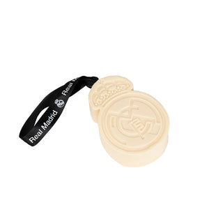 A cream-colored Real Madrid soccer puck-shaped accessory with an embossed club crest, attached to a black wrist strap printed with the white Real Madrid logo and name.