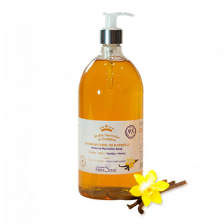 A bottle of Freelins Natural de Marseille body soap in a transparent amber-colored bottle with a white pump dispenser, shown on a white background with a yellow flower and cinnamon sticks graphic at the bottom right.