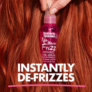 A hand holds a bottle of Umberto Giannini No More Frizz Curl Serum against a background of frizzy, coppery-red hair. Large white text at the bottom reads 'INSTANTLY DE-FRIZZES'.