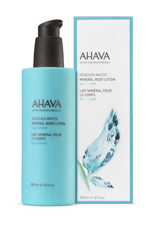 A bottle of AHAVA Deadsea Water Mineral Body Lotion in a light blue bottle with a black pump, shown next to its white and light blue packaging box on a white background.