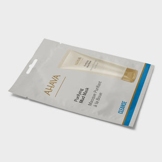AHAVA Purifying Mud Mask in a silver resealable pouch with a printed tube of the mask and a blue and gold stripe on the right side, photographed on a light gray background.