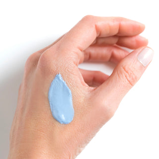 Hand with a small amount of blue cream on the wrist against a white background