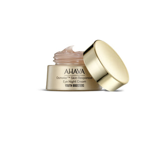 AHAVA Osmoter Skin-Response Eye Night Cream in a gold jar with its lid off, showing the cream inside, on a white background.
