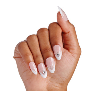 A hand with long almond-shaped press-on nails featuring a glossy pink and white French tip design with silver rhinestone accents, shown against a plain white background.