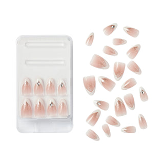 Almond-shaped press-on nails with a glossy nude-pink gradient and a small silver rhinestone accent at the tip, shown in a clear plastic tray next to several loose nails on a white background.