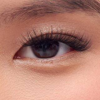 Close-up of a person's eye with long, dark eyelashes and well-defined eyebrow.