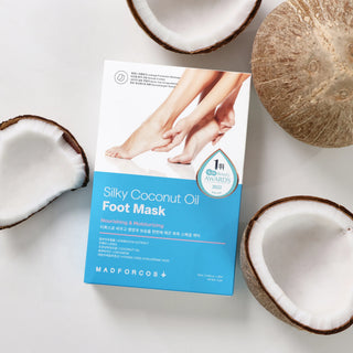 A flat-lay of the MADFORCOS Silky Coconut Oil Foot Mask box, surrounded by sliced coconuts on a clean white background.