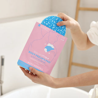 A person holds a pink package of Mad For Ge body peeling pads, with a blue peel sheet partially pulled out, in a bright bathroom setting.