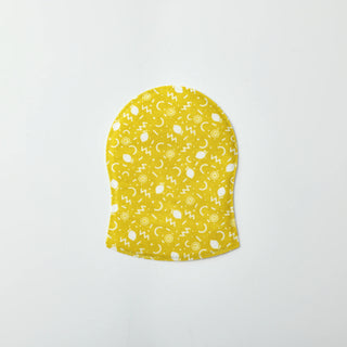 A yellow fabric headband with a white abstract pattern of circles, dots, and geometric shapes, shown flat against a light gray background.