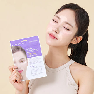 A woman with closed eyes and under-eye mask patches holds a purple and white package of MADFONCOSA Wrinkle Mover Patch Eye Masks against a warm beige background.
