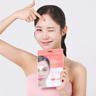 A woman with dark hair pulled back wears a pink strapless top and holds a package of MAFORDORA Wrinkle Repairing Pouch facial masks. She points to her forehead with one hand while winking at the camera, set against a clean light gray background.