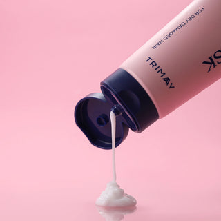 Pink bottle of Trimay hair product with white cream being squeezed out on a pink background