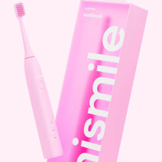 A pink electric toothbrush shown next to its matching pink packaging box with large white 'nismile' branding on a pale pink background.