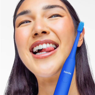 A close-up lifestyle shot of a woman smiling while holding a blue electric toothbrush branded 'hismile' against a clean white background.