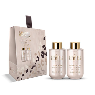 The Luxury Bathing London Cashmere Musk & Amber gift set, featuring a beige and black leopard-print box alongside two frosted glass bottles with gold caps: a body wash and a body lotion, each 500 ml.