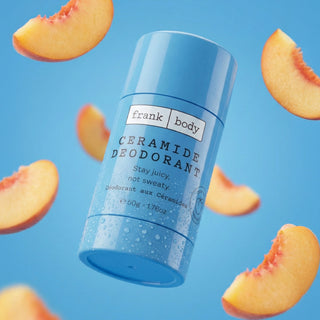 A blue Frank Body Ceramide Deodorant tube floating against a bright blue background with peach slices arranged around it. The label reads 'frank body CERAMIDE DEODORANT Stay juicy, not sweaty'.