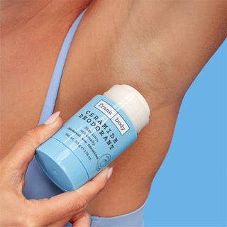 A light blue Frank | body Ceramide Deodorant stick being applied to a person's underarm against a solid blue background.