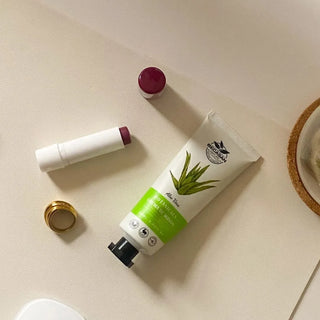 Tub de crema Becasan Aloe Vera si un balsam de buze, pe o suprafata bej