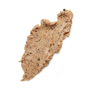 A smear of light brown cosmetic or food paste with small black specks, photographed on a clean white background.