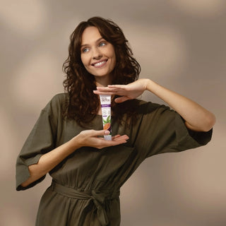 Femeie tinand in mana pasta de dinti Ecodenta cu aroma de fructul pasiunii, pe fundal neutru