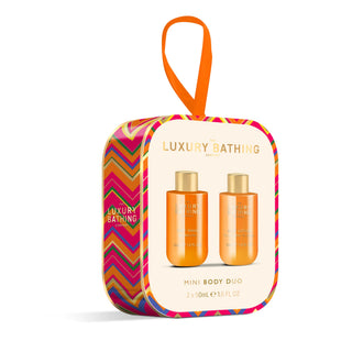 Luxury Bathing London Mini Body Duo gift set in a colorful zippered pouch with an orange hanging loop. The front features a cream panel showing two orange bottles with gold caps, and the sides have a vibrant multicolor chevron pattern.