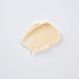 A swatch of creamy, pale beige cosmetic cream or foundation, photographed on a clean, light gray background.