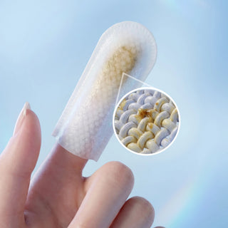 A close-up of a finger wearing a translucent, textured adhesive pad or plug insert, with a circular inset showing a magnified view of the internal textured surface against a soft light blue background.